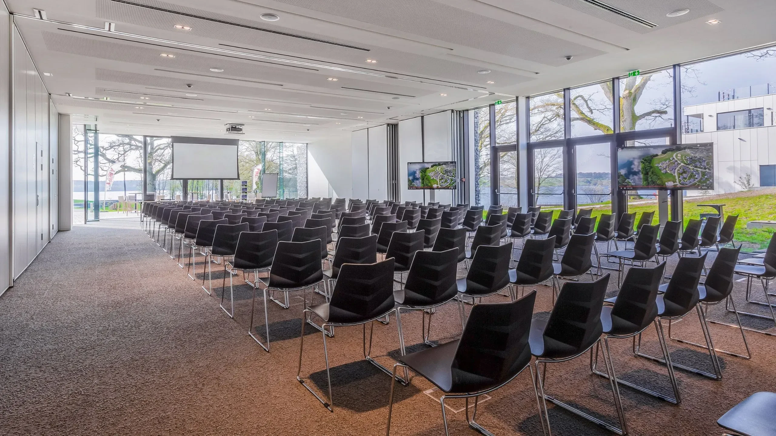 Salle de conférence avec sièges vides et écran.