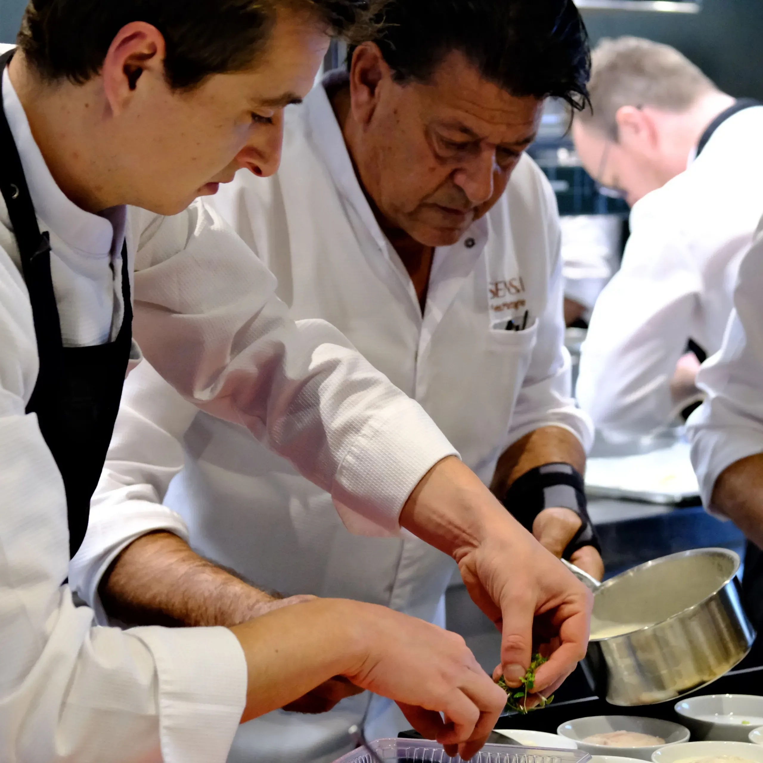 Chefs préparant un plat en cuisine.
