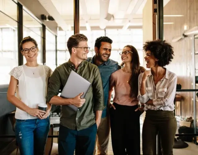 Groupe de collègues souriants dans un bureau moderne.