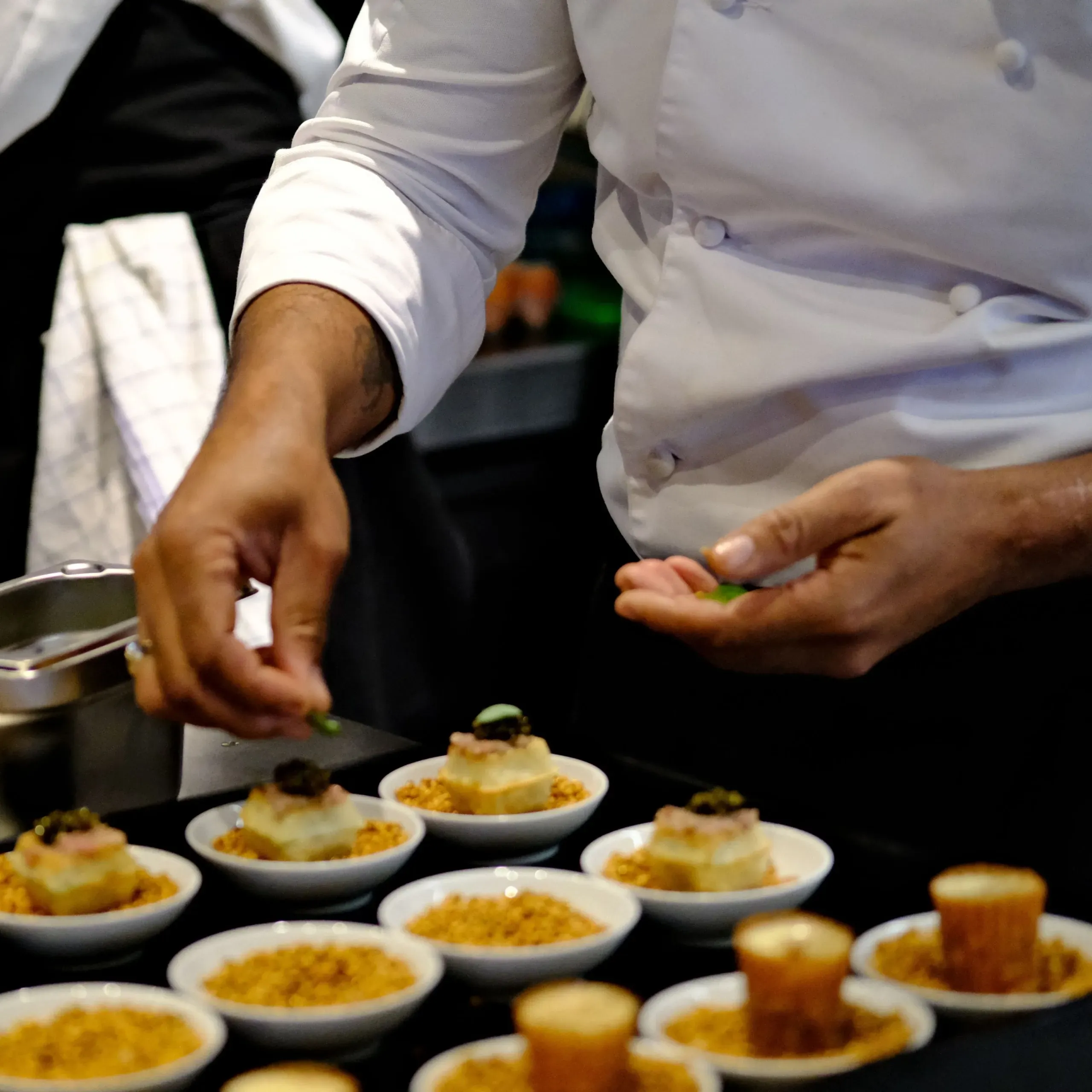 Chef préparant des amuse-bouches raffinés sur assiettes.