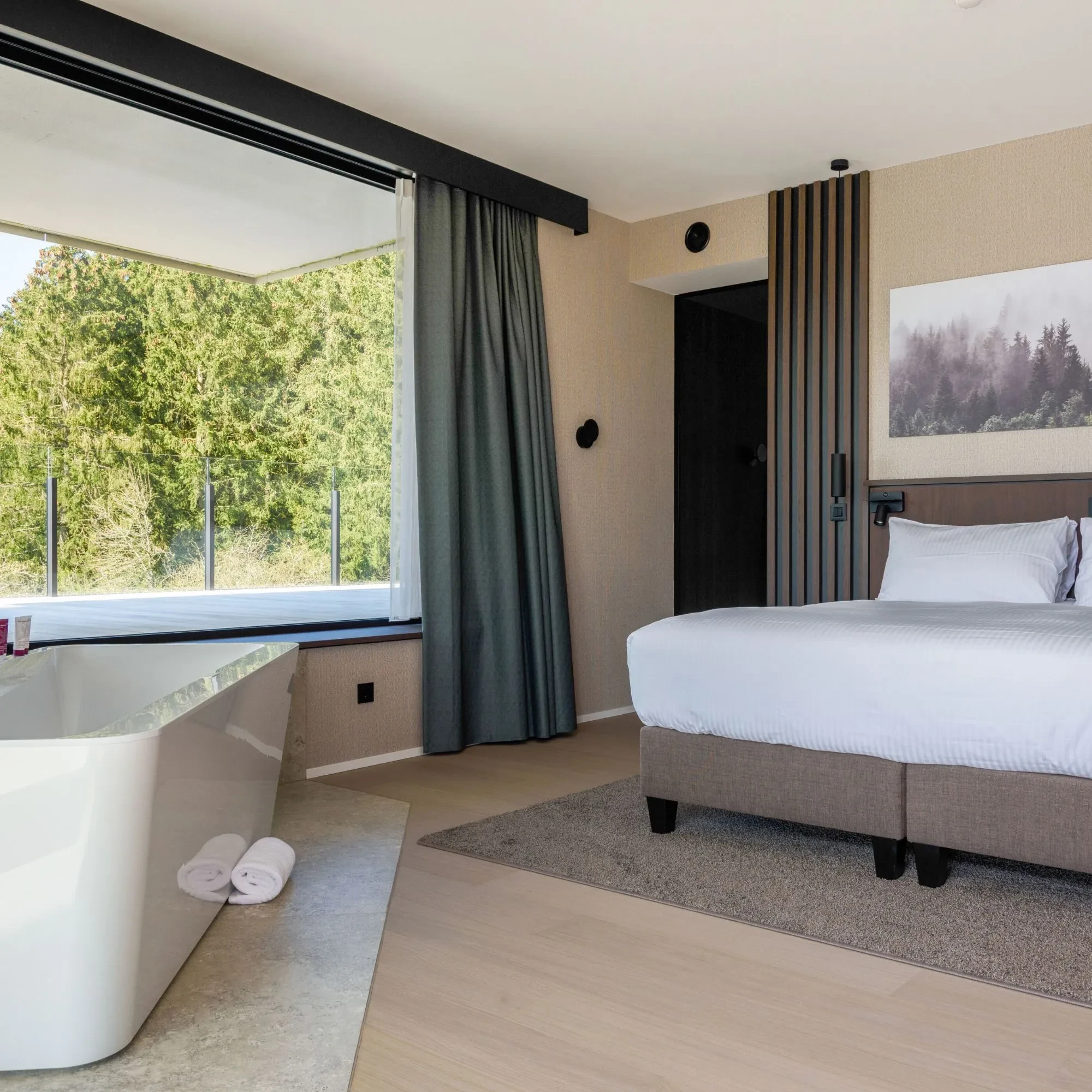 Chambre avec baignoire et vue sur forêt.